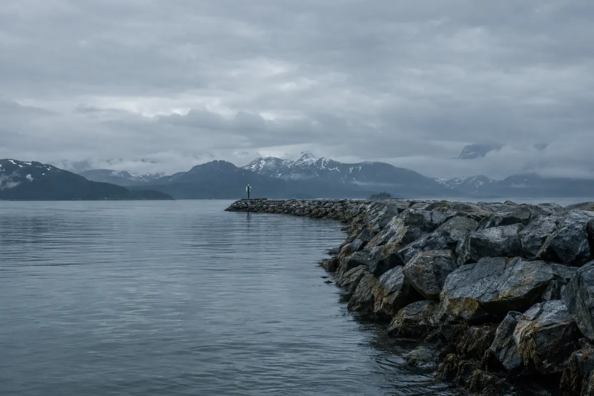 Stone breakwater of a remote Alaskan harbor under an overcast sky